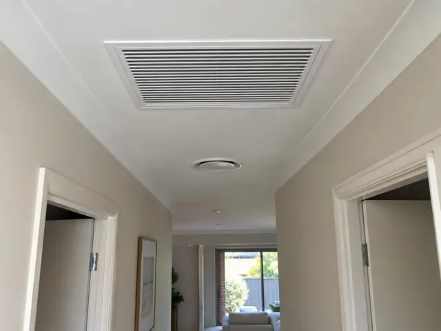 Ceiling return-air grille in a painted hallway with doorways and living room visible in Pimpama